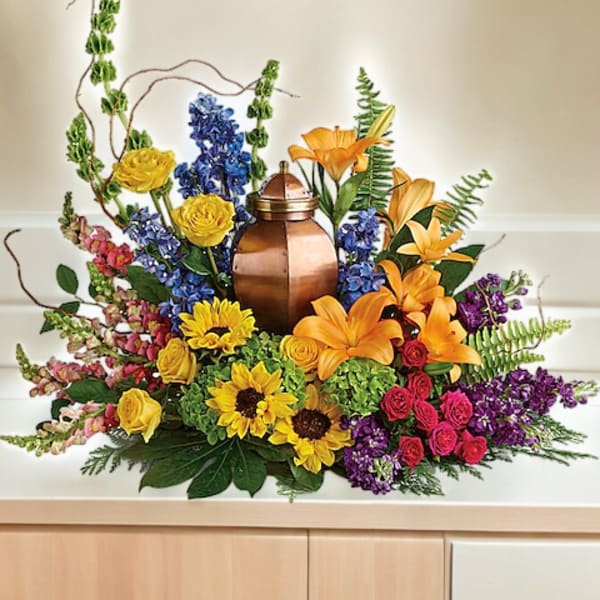 Colorful floral arrangement around a copper urn