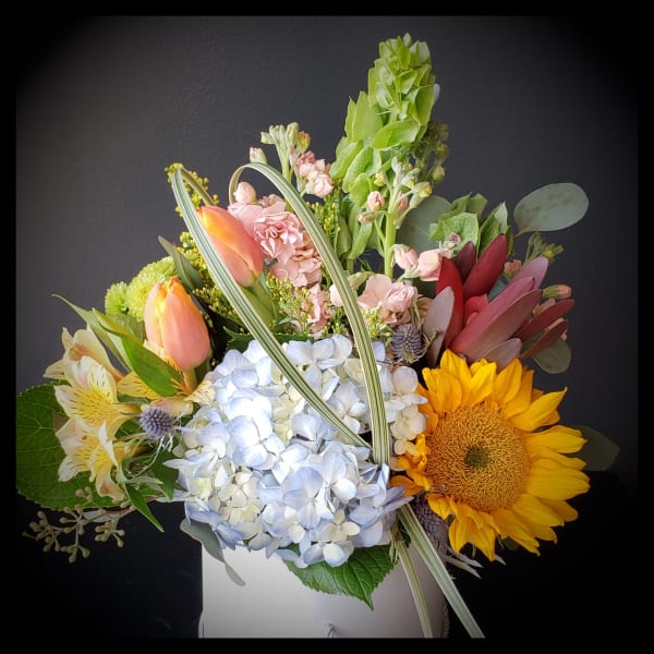 Mixed bouquet with sunflowers, hydrangeas, tulips, and pink blooms in a white box