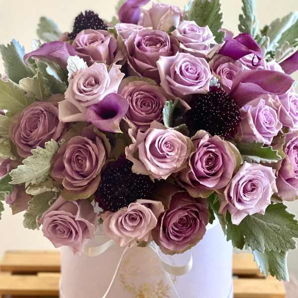 Lavender roses and dark calla lilies in a white hat box