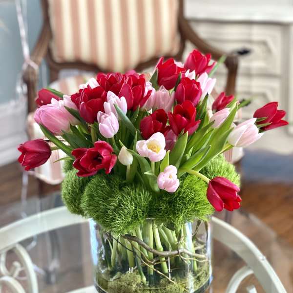 Red and pink tulips arranged in a clear glass vase.