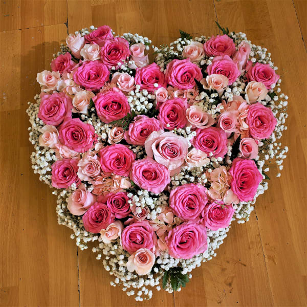 Heart-shaped bouquet of pink and blush roses with white filler flowers