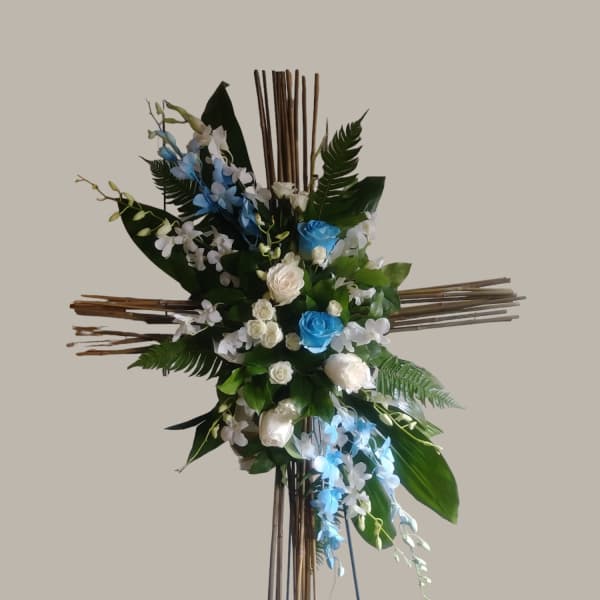 Cross-shaped floral arrangement with blue and white flowers on a wooden stand
