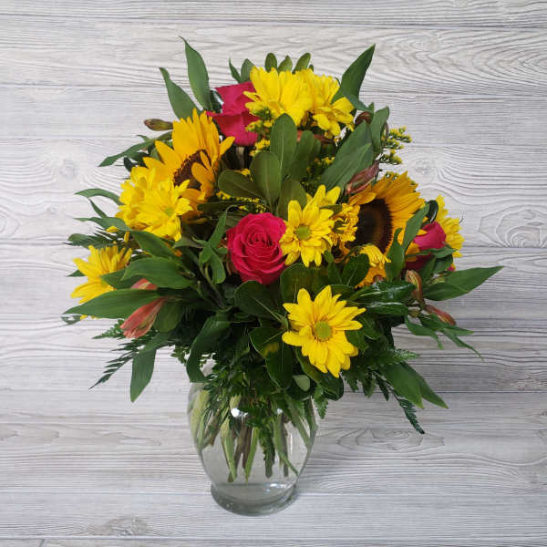 Bouquet of yellow daisies and pink roses in a clear glass vase