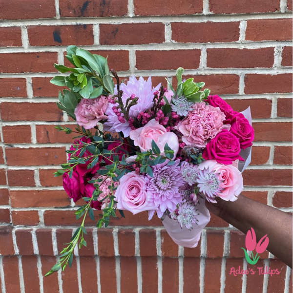 Handheld bouquet of pink and lavender flowers with greenery