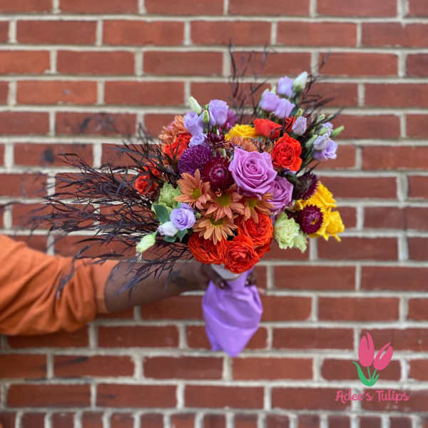 Colorful bouquet of roses and mixed flowers with dark feathery accents
