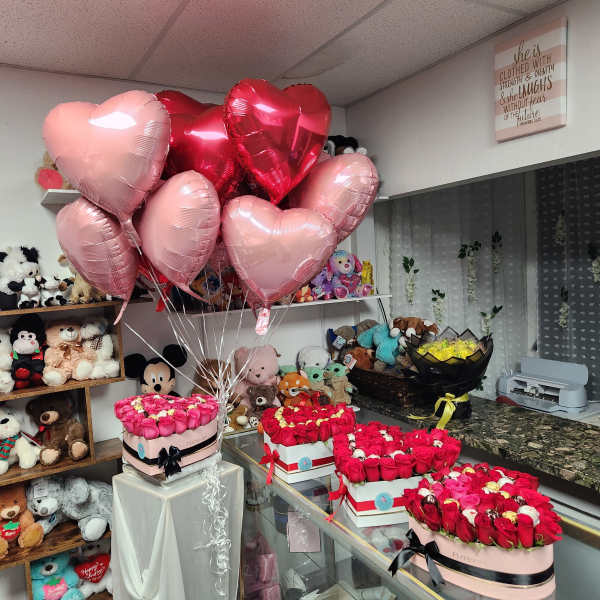 Heart-shaped balloons above boxed rose arrangements in a gift shop
