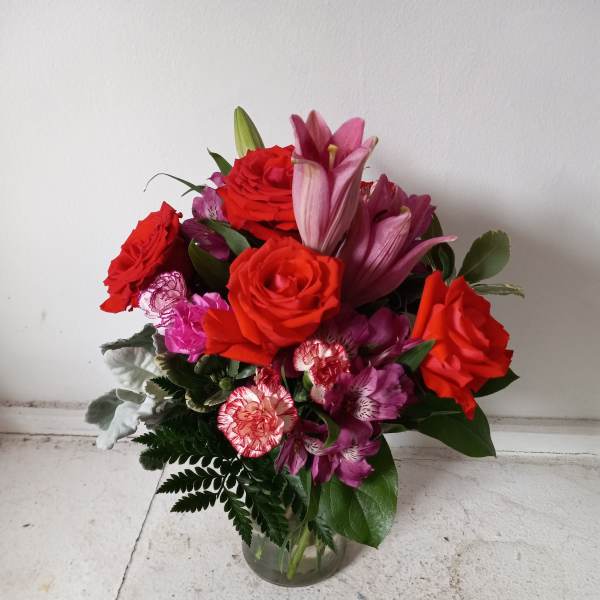 Bouquet of red roses and pink lilies in a clear glass vase