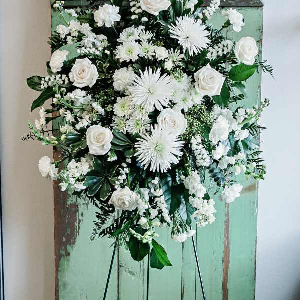 White floral standing spray on a black easel