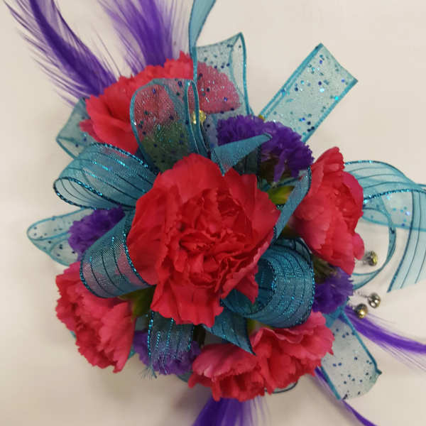 Bright pink carnation corsage with blue ribbon and purple feathers
