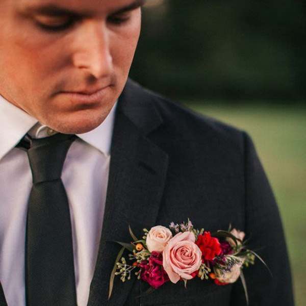 Boutonniere with pink roses and red flowers on a suit jacket