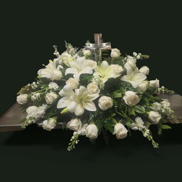 White floral casket spray with a silver cross centerpiece
