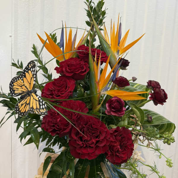 Red roses with orange bird-of-paradise flowers and a butterfly accent