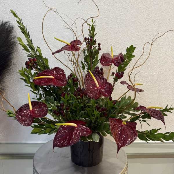 Arrangement of burgundy anthuriums in a black vase