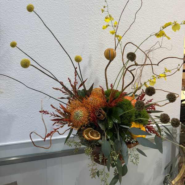 Tall autumn floral arrangement with orange blooms and decorative branches
