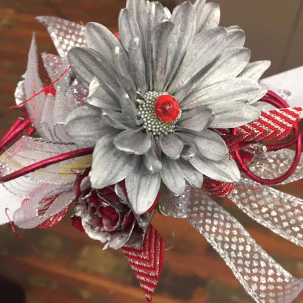 Silver artificial flower corsage with red ribbon accents