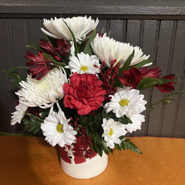 Red and white mixed flower arrangement in a white holiday container