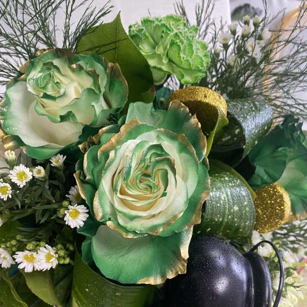 Green and white floral arrangement with gold accents and a black firefighter helmet