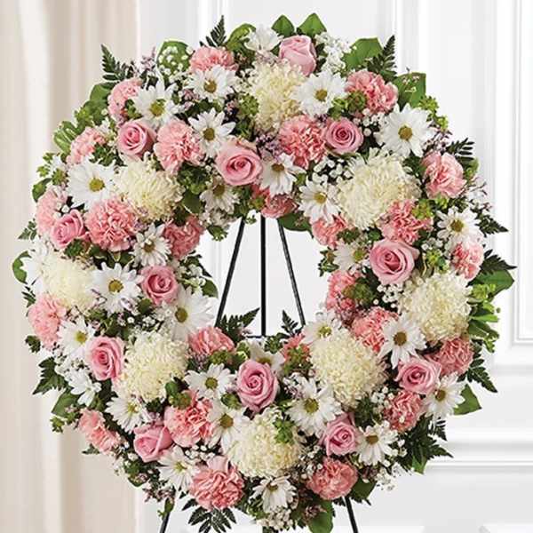 Heart-shaped floral wreath with pink and white flowers on a stand