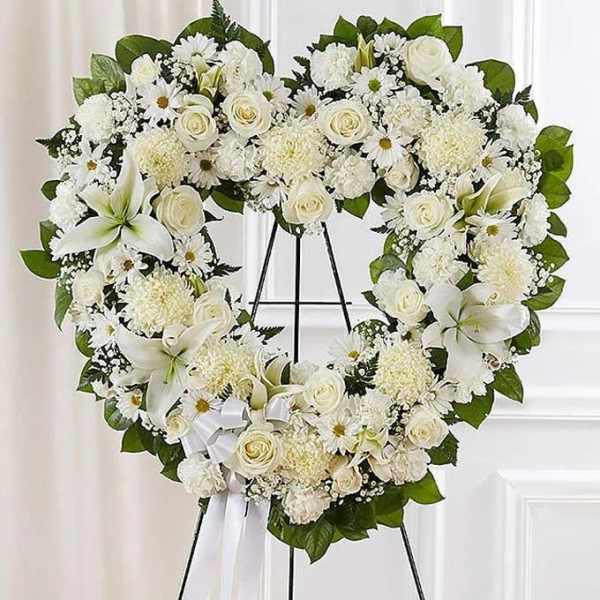 White floral heart wreath on an easel with roses and lilies