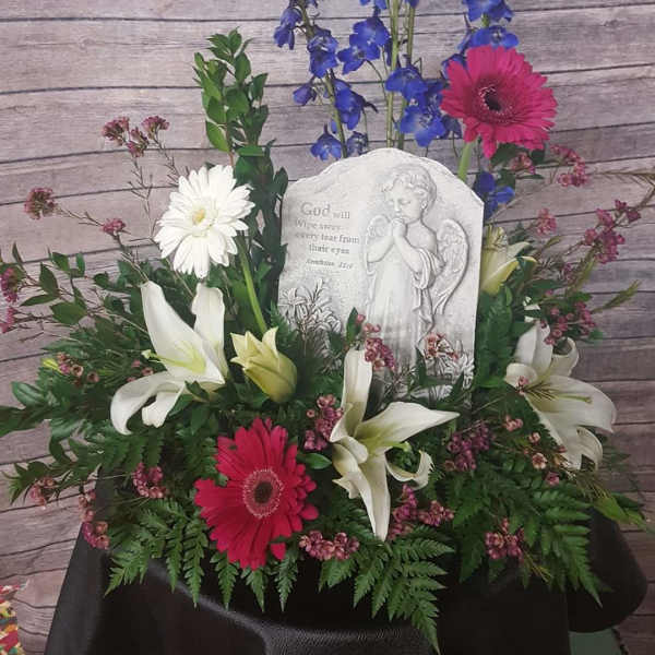 Sympathy floral arrangement with lilies, gerberas, and a memorial plaque