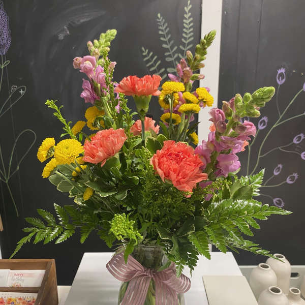 Mixed bouquet in a glass vase with pink, coral, and yellow blooms