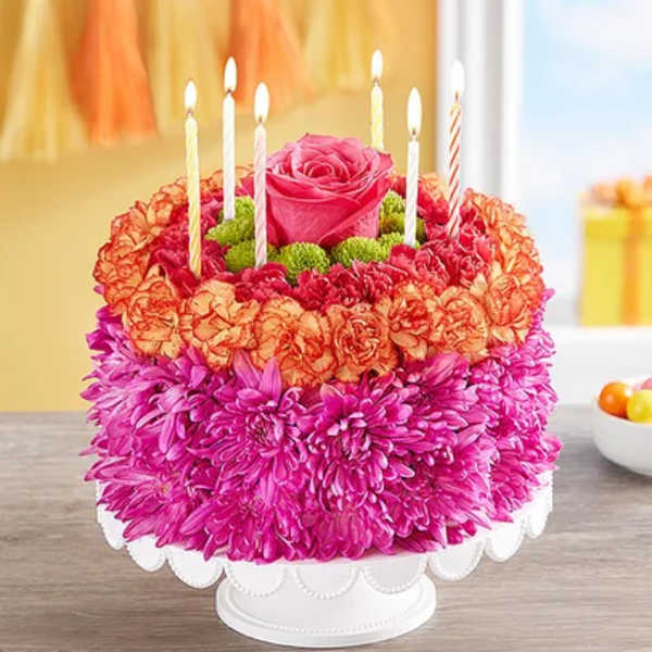 Round floral cake with candles and a pink rose topper