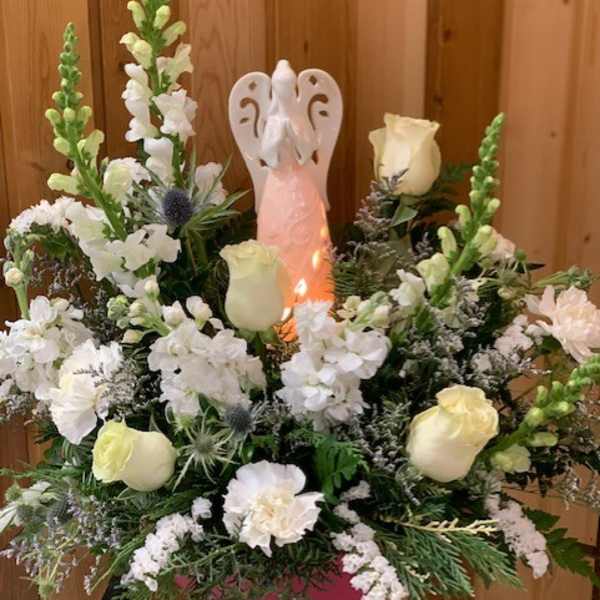 White floral arrangement with an angel figurine in the center