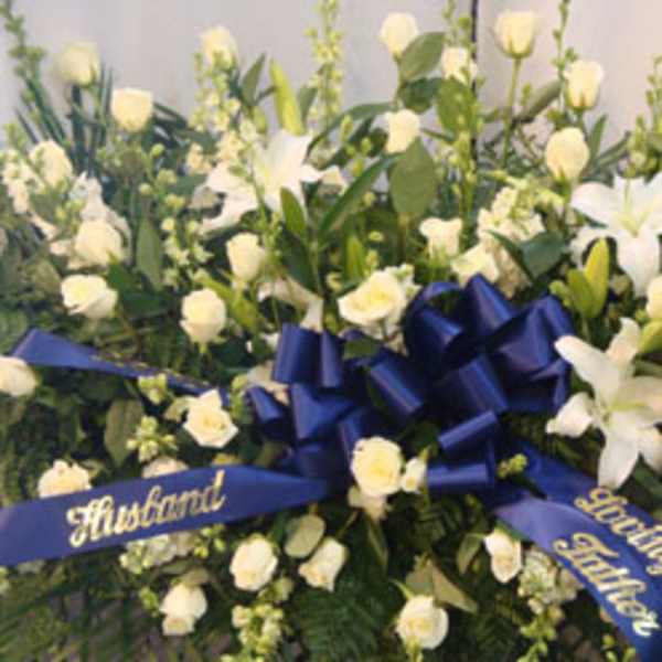 White floral funeral spray with blue ribbons and a central bow