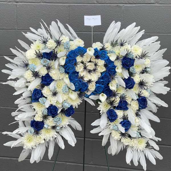 Heart-shaped floral standing spray with blue and white roses and feathers