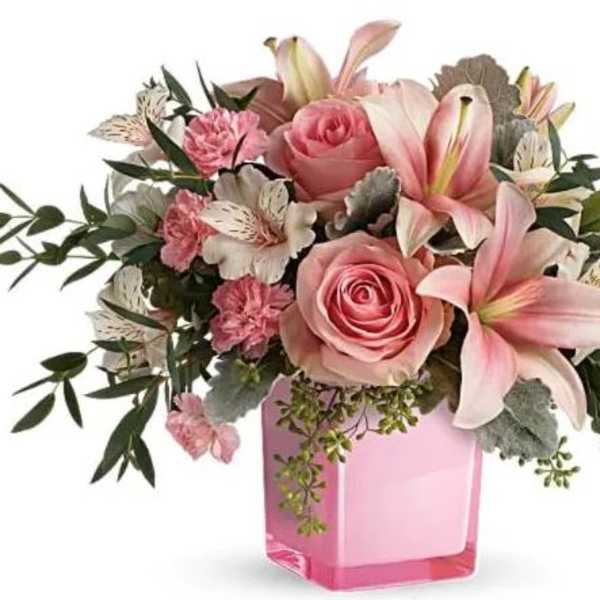 Pink roses and lilies arranged in a pink glass vase