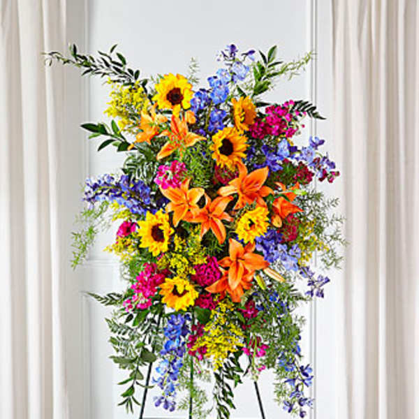 Tall standing spray with sunflowers, lilies, and blue flowers