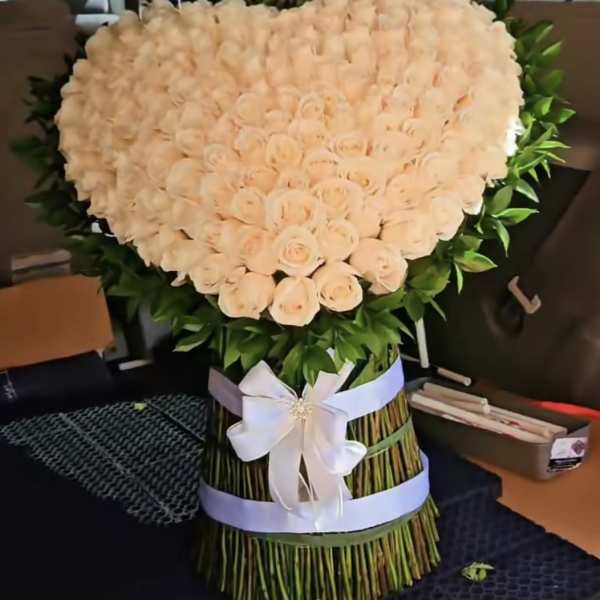 Heart-shaped bouquet of pale peach roses with a white ribbon