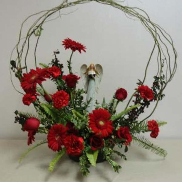 Red floral arrangement with an angel figurine in a circular twig frame