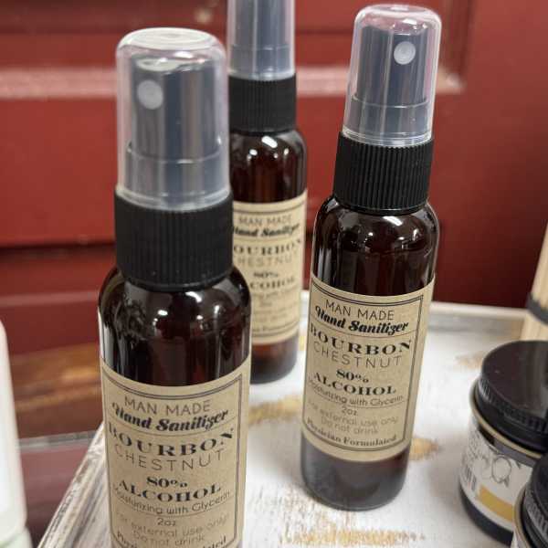 Three spray bottles of bourbon chestnut hand sanitizer on a tray