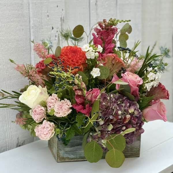 Mixed floral arrangement in a wooden box with pink, white, and purple blooms