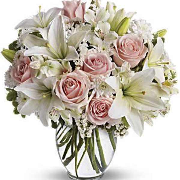 Bouquet of pink roses and white lilies in a clear glass vase