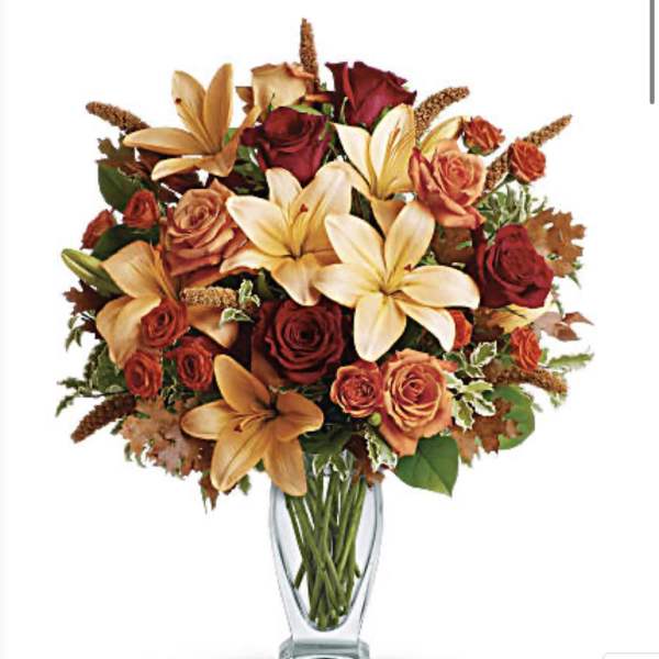 Bouquet of orange lilies and red roses in a clear glass vase