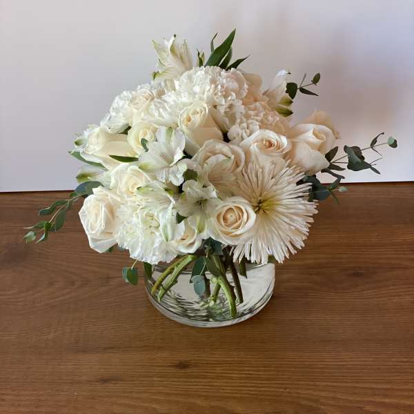 White roses and carnations in a clear glass bowl vase