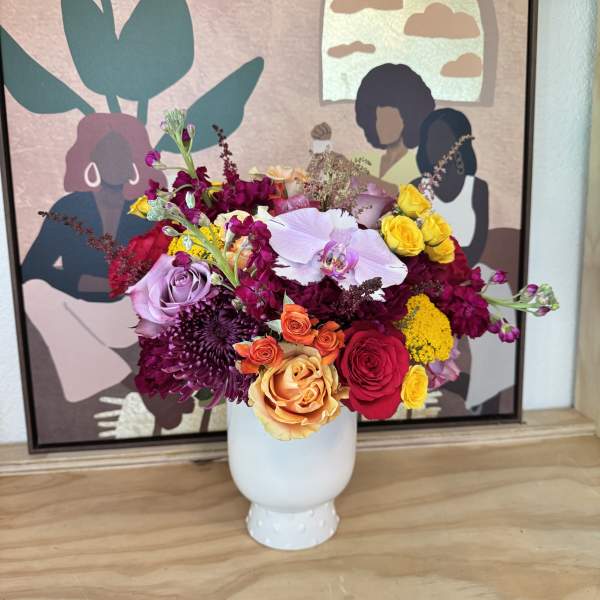 Mixed bouquet of roses, orchids, and chrysanthemums in a white vase