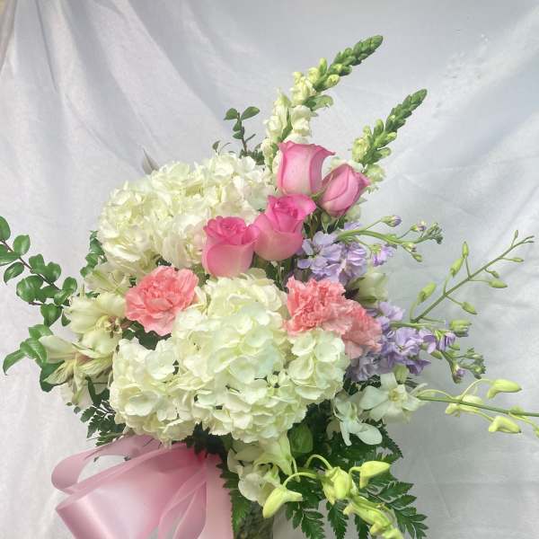 Bouquet of pink roses, white hydrangeas, and lavender flowers in a glass vase