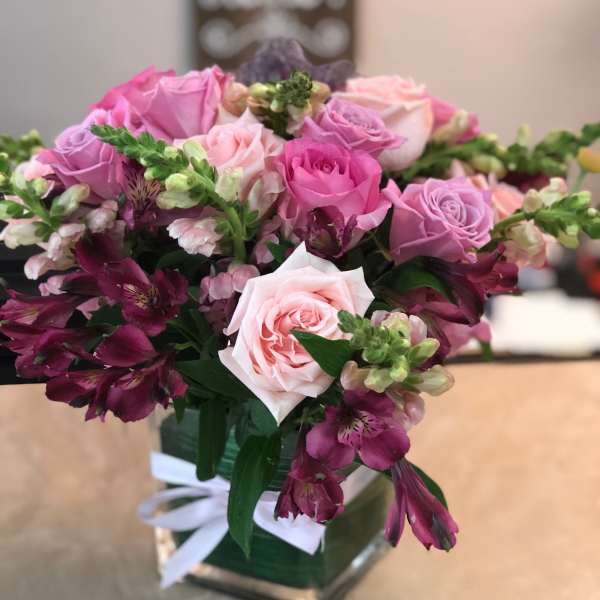 Pink and purple rose bouquet in a square vase