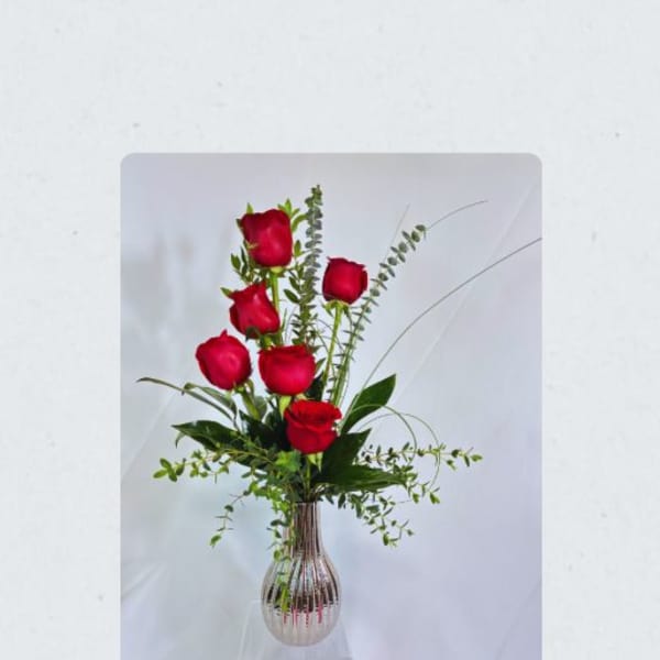 Tall vase arrangement of red roses with airy greenery