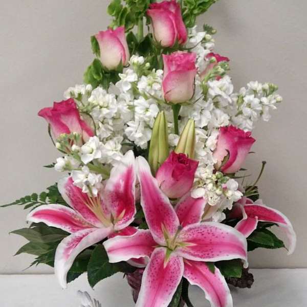 Pink roses and lilies arranged in a vase with white filler flowers