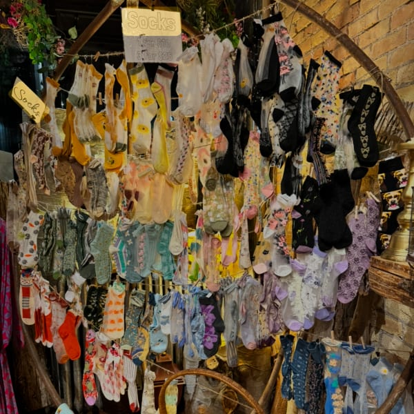 Display of colorful socks hanging on a rack with handwritten signs