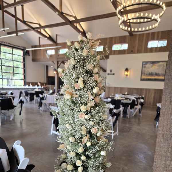Tall floral arrangement with white and blush roses in a reception hall