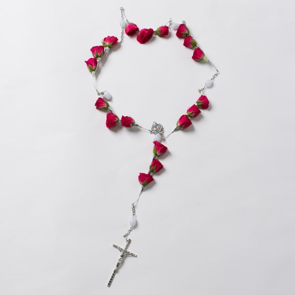 Pink rosebud rosary with a silver cross on a white background