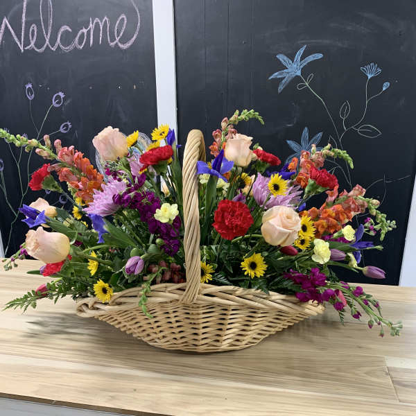 Mixed flowers arranged in a wicker basket on a table