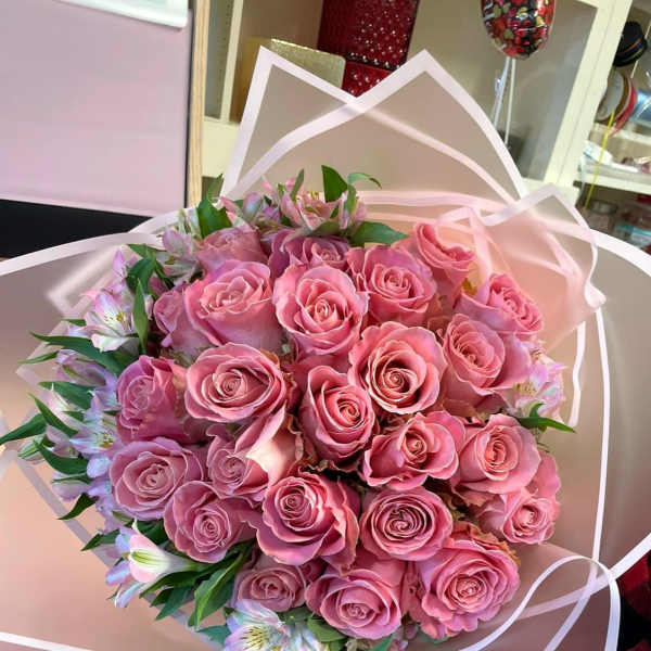 Bouquet of pink roses with small pale lilies wrapped in blush paper