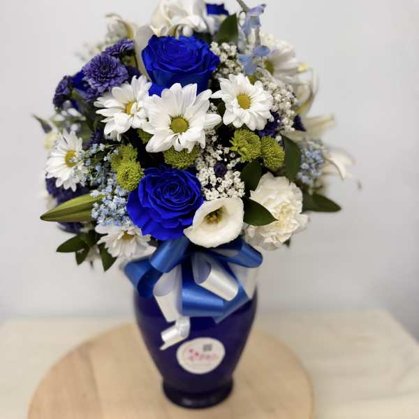Blue and white flower bouquet in a dark vase with a ribbon