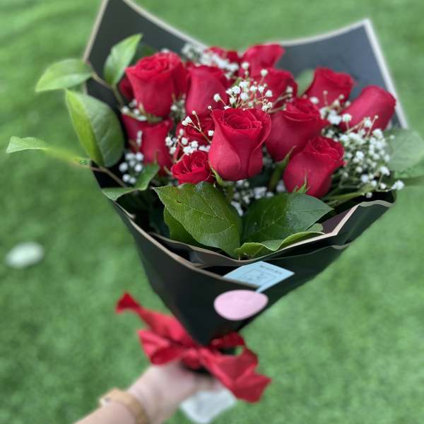 Bouquet of red roses with baby's breath in black wrapping
